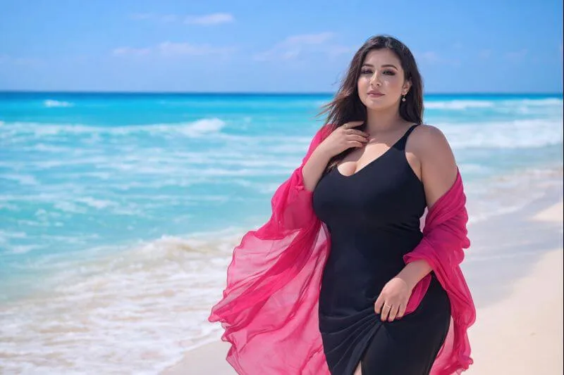 امرأة بإطلالة أنثوية أنيقة على الشاطئ تعكس الثقة والجمال الطبيعي